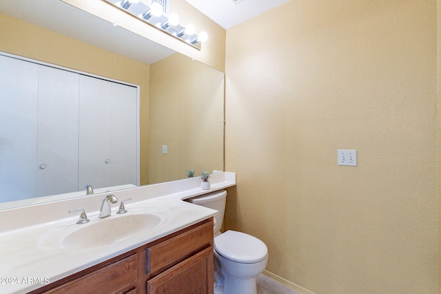 bathroom with baseboards, vanity, and toilet