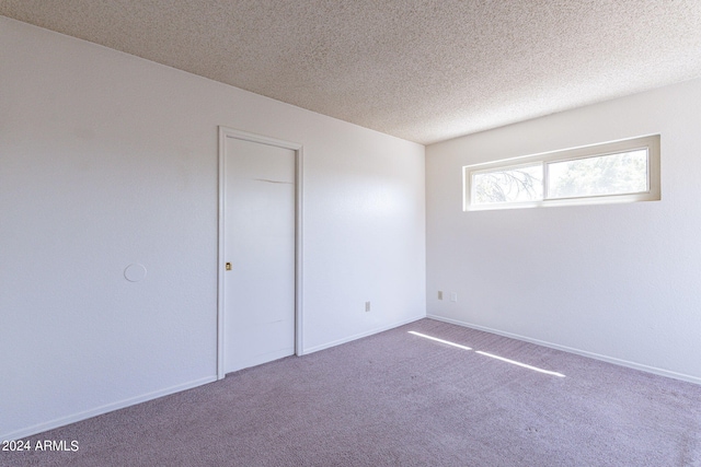 carpeted empty room with baseboards and a textured ceiling