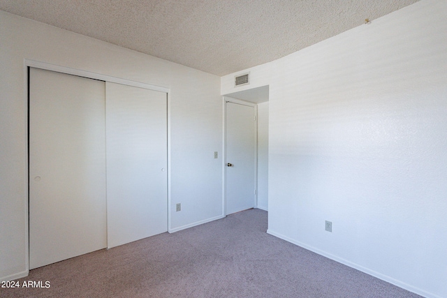 unfurnished bedroom with carpet floors, a closet, visible vents, and a textured ceiling