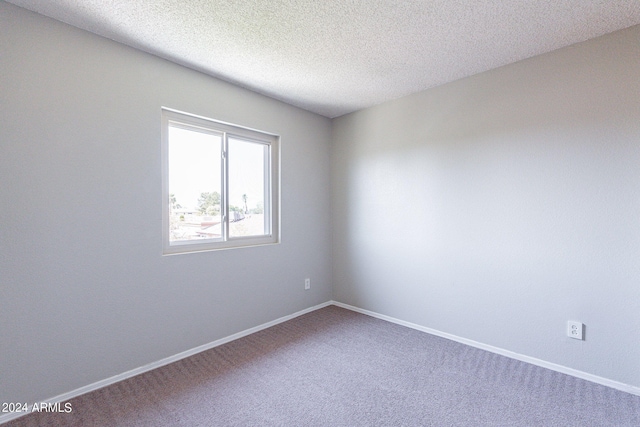 carpeted spare room with a textured ceiling and baseboards