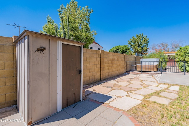 view of patio / terrace featuring an outbuilding, a storage unit, and a fenced backyard