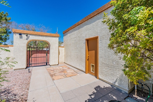 exterior space featuring a gate, fence, and stucco siding