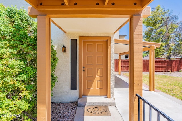 entrance to property with fence and stucco siding