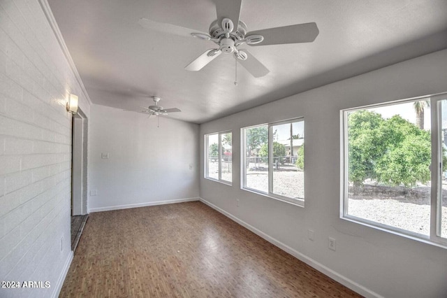 unfurnished room with ornamental molding, hardwood / wood-style flooring, ceiling fan, and brick wall