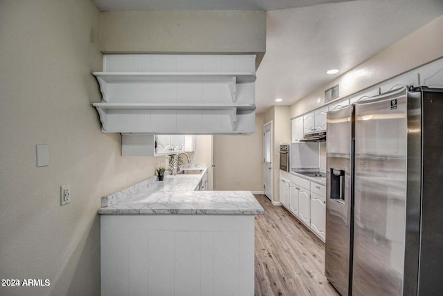 kitchen with white cabinets, kitchen peninsula, light hardwood / wood-style flooring, sink, and appliances with stainless steel finishes