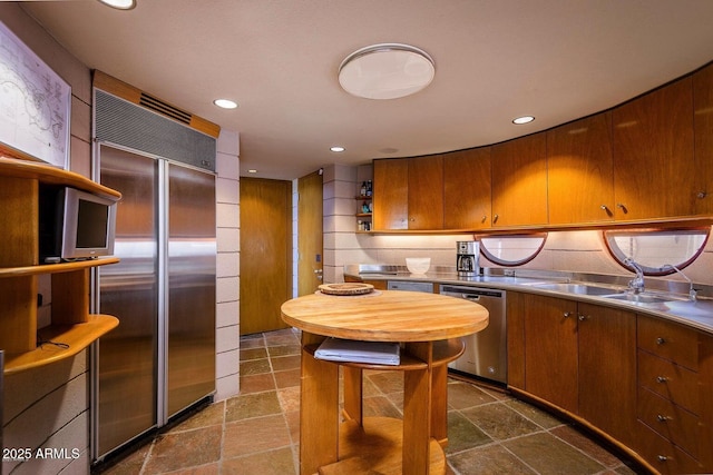 kitchen with appliances with stainless steel finishes, stainless steel counters, and sink