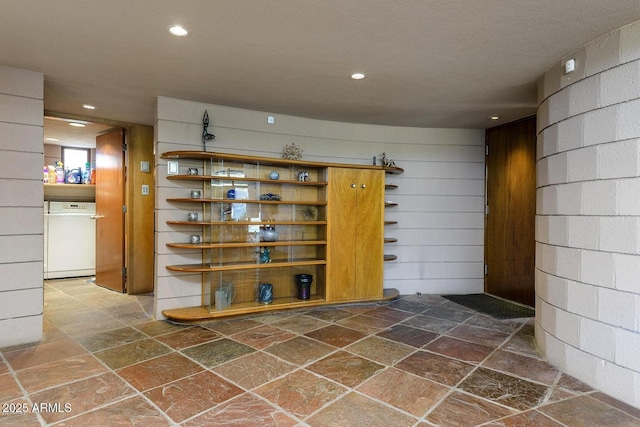 bar featuring white dishwasher and wooden walls