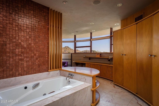 bathroom featuring tiled tub and a textured ceiling