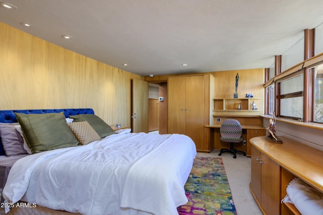 carpeted bedroom featuring built in desk and wood walls