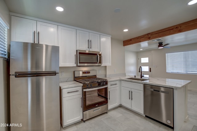 kitchen with white cabinets, kitchen peninsula, stainless steel appliances, sink, and ceiling fan