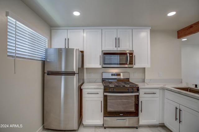 kitchen featuring appliances with stainless steel finishes, white cabinets, and light stone counters