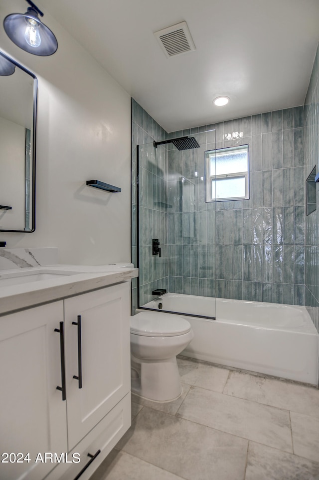 full bathroom featuring tiled shower / bath combo, vanity, toilet, and tile flooring