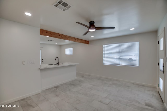 unfurnished living room featuring beamed ceiling, sink, ceiling fan, and light tile flooring