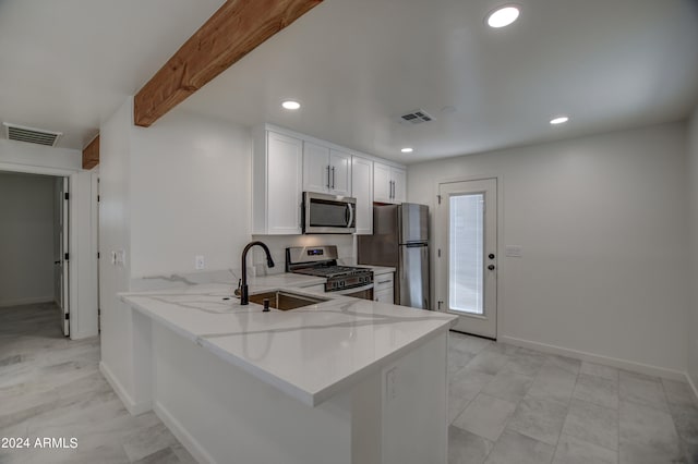 kitchen with light tile floors, white cabinets, sink, stainless steel appliances, and kitchen peninsula