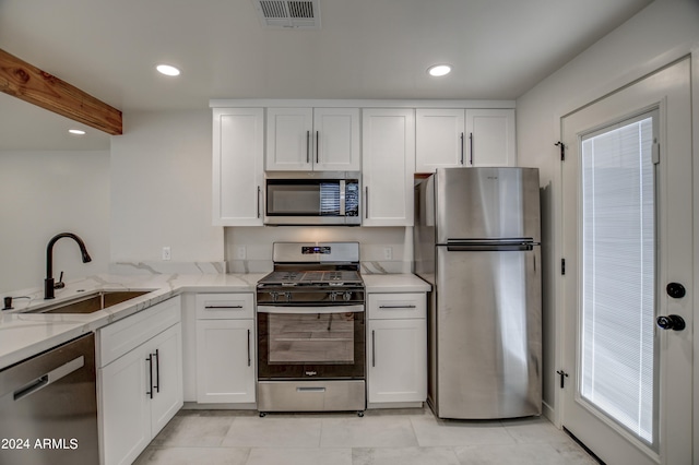 kitchen featuring light stone counters, appliances with stainless steel finishes, light tile floors, white cabinets, and sink