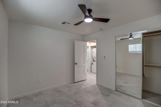 unfurnished bedroom featuring a closet, ceiling fan, light tile floors, and washer / dryer