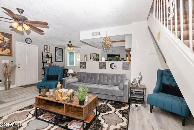 living room with ceiling fan with notable chandelier and light wood-type flooring