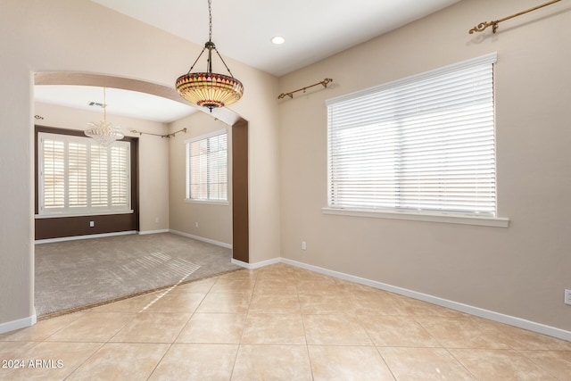 tiled empty room featuring an inviting chandelier