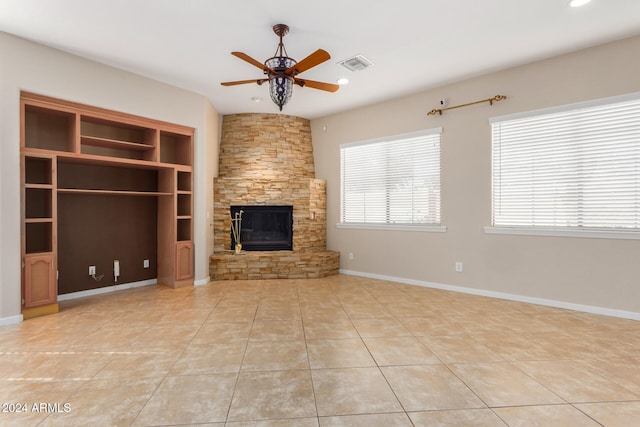 unfurnished living room featuring built in shelves, ceiling fan, a fireplace, and light tile patterned floors