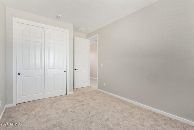 unfurnished bedroom featuring light carpet and a closet