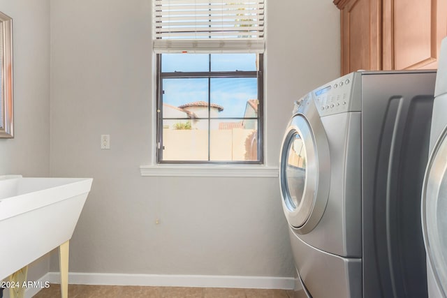 washroom featuring light tile patterned floors, cabinets, and washer / dryer