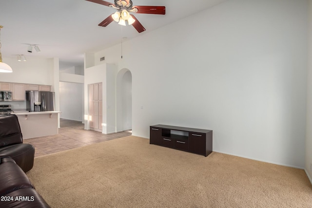 10735 W Bermuda Dr, Avondale, AZ 85392 - unfurnished living room with arched walkways, ceiling fan, light carpet, a high ceiling, and light tile patterned floors