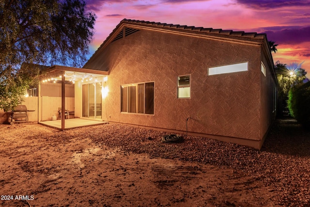 10735 W Bermuda Dr, Avondale, AZ 85392 - back of house at dusk with a patio and stucco siding