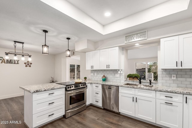 kitchen featuring decorative light fixtures, a peninsula, stainless steel appliances, white cabinetry, and a sink