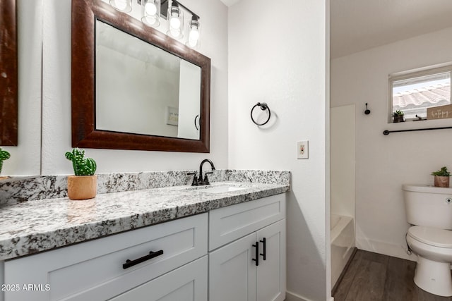 bathroom featuring toilet, vanity, shower / tub combination, wood finished floors, and baseboards