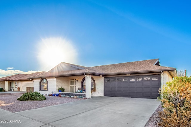 ranch-style house featuring a garage, brick siding, concrete driveway, and roof with shingles