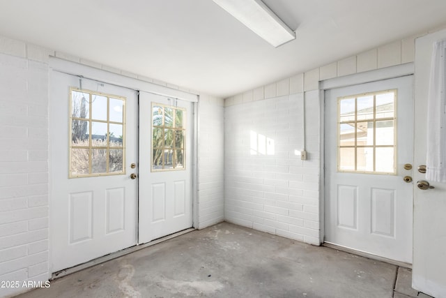 doorway to outside featuring unfinished concrete flooring