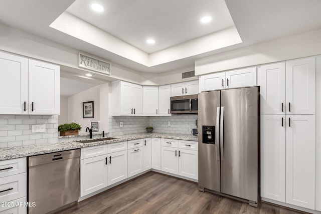 kitchen with white cabinets, stainless steel appliances, and a raised ceiling