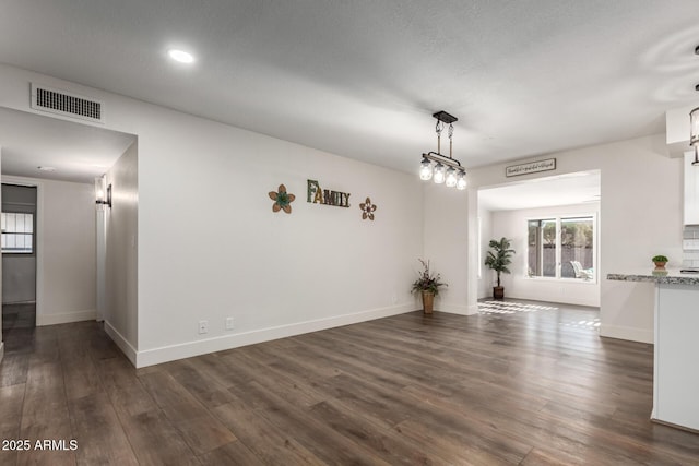 spare room with dark wood-style flooring, visible vents, and baseboards