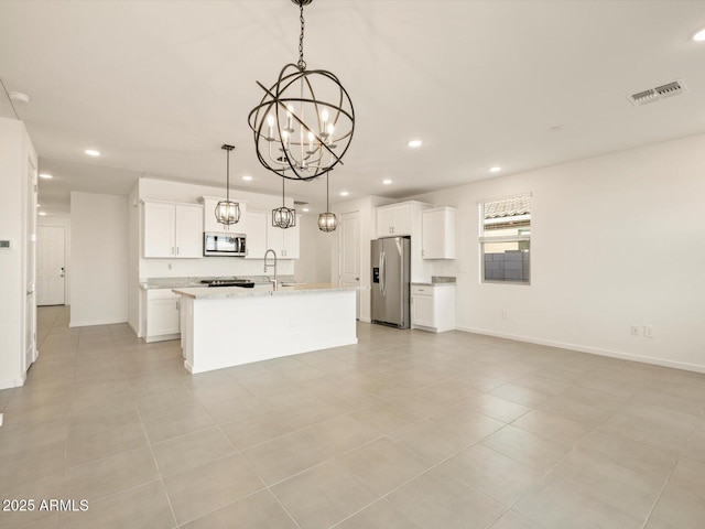 kitchen with appliances with stainless steel finishes, a notable chandelier, pendant lighting, a kitchen island with sink, and white cabinets