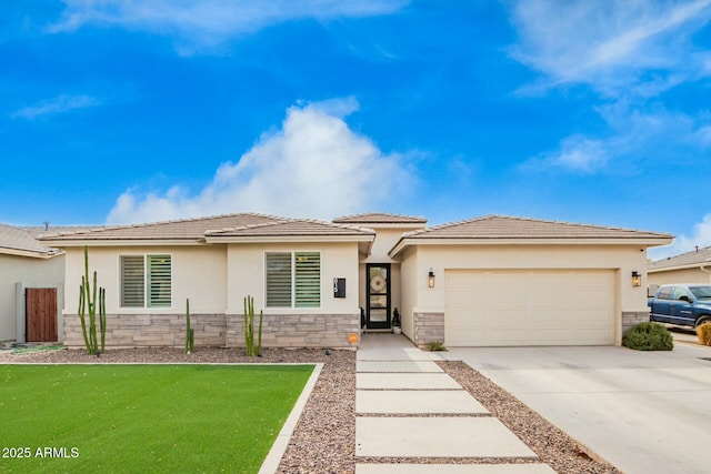 prairie-style home featuring stone siding, an attached garage, concrete driveway, and stucco siding