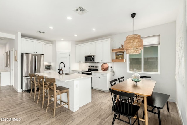 kitchen with visible vents, stainless steel appliances, a sink, and a kitchen breakfast bar