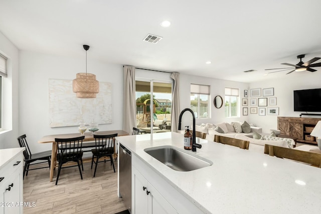 kitchen with visible vents, open floor plan, a sink, light wood-style floors, and stainless steel dishwasher