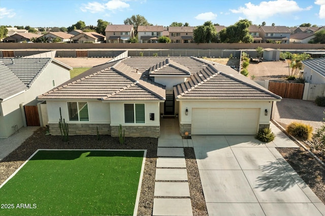 view of front facade with stone siding, a residential view, an attached garage, fence, and stucco siding