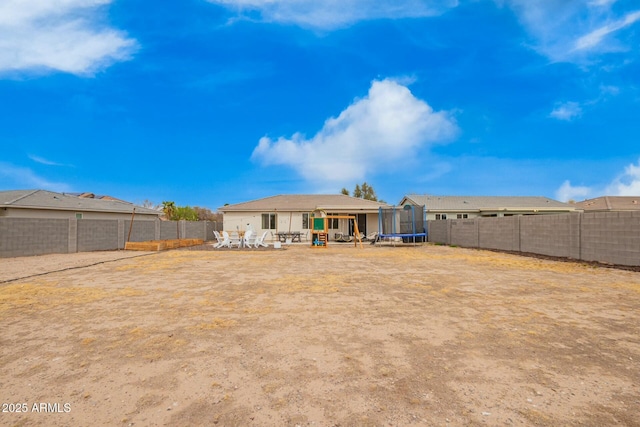 back of house featuring a fenced backyard, a trampoline, and a patio