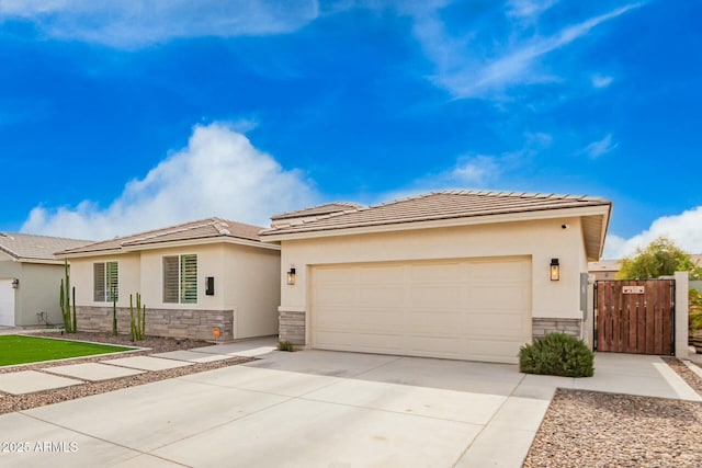 prairie-style house with a garage, stone siding, concrete driveway, a gate, and stucco siding