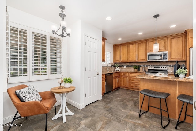 kitchen with light stone countertops, a healthy amount of sunlight, appliances with stainless steel finishes, and pendant lighting