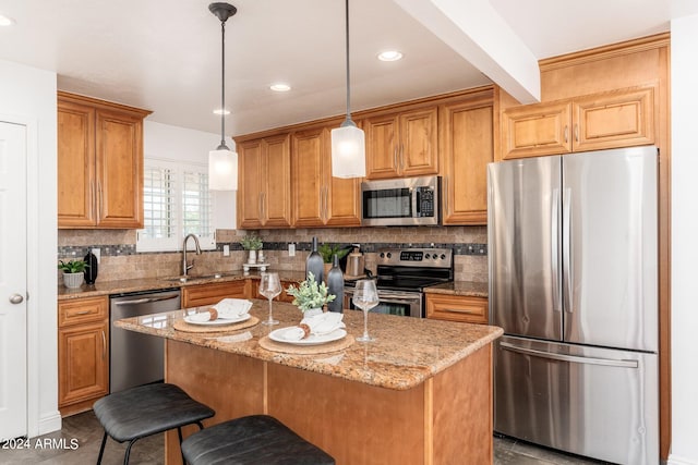 kitchen with light stone countertops, stainless steel appliances, sink, decorative light fixtures, and a center island