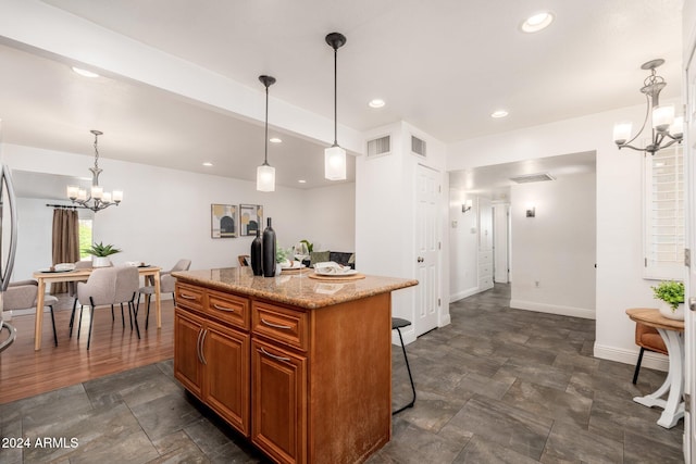 kitchen featuring light stone countertops, a center island, a chandelier, and pendant lighting