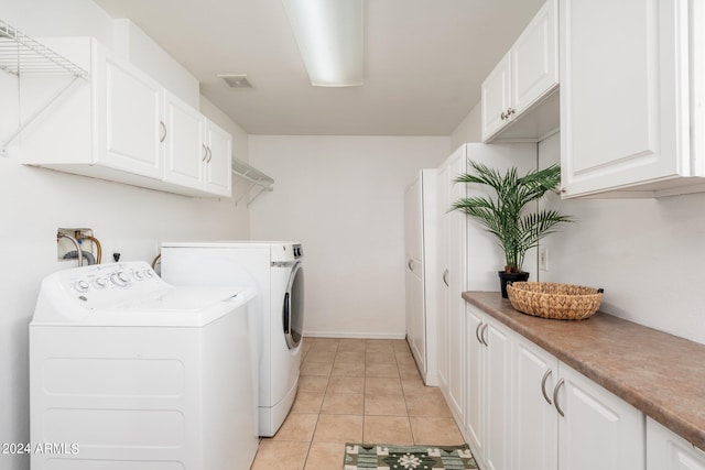 washroom featuring washer and clothes dryer, light tile patterned floors, and cabinets