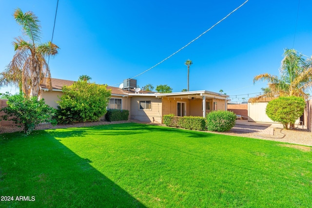 back of property with a yard and central AC unit