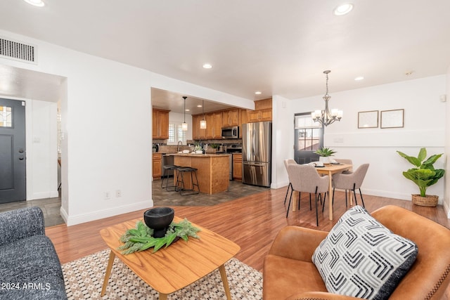 living room featuring a wealth of natural light, sink, a notable chandelier, and light hardwood / wood-style floors