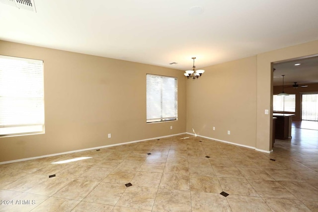 empty room with light tile patterned floors and a chandelier