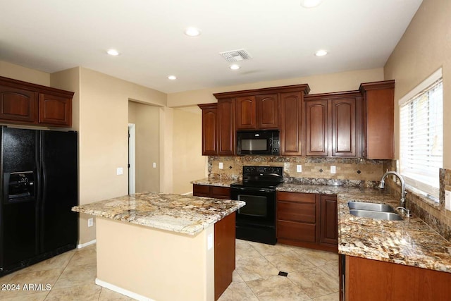 kitchen with a kitchen island, black appliances, light stone countertops, sink, and tasteful backsplash