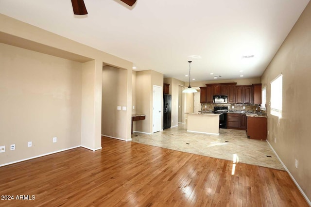 kitchen with backsplash, light wood-type flooring, sink, decorative light fixtures, and stainless steel electric range oven