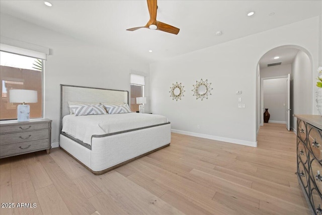 bedroom featuring visible vents, light wood finished floors, baseboards, recessed lighting, and arched walkways